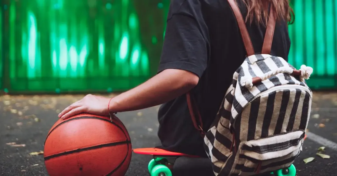 Young athlete sitting on a skateboard with a basketball, ready to return to sport after hip arthroscopy