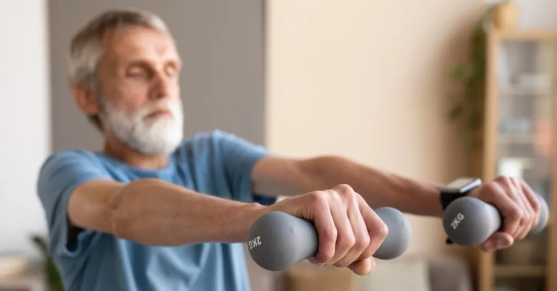 Senior man performing light dumbbell front raises for shoulder strengthening during Phase 3 recovery after anatomic total shoulder arthroplasty.