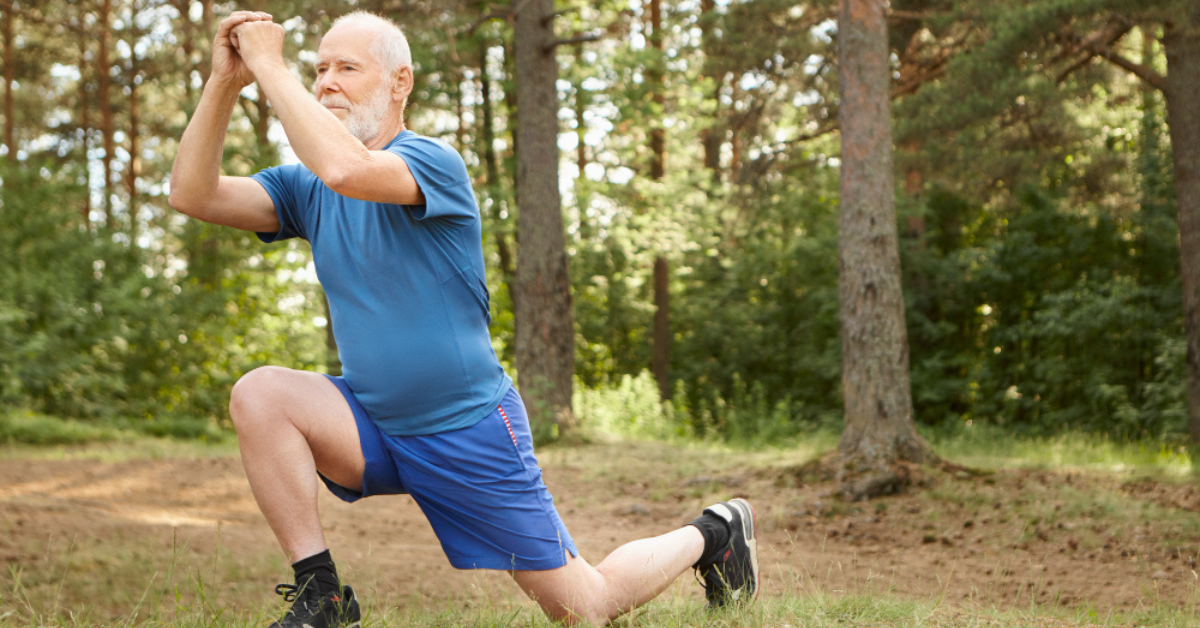 Senior man performing overhead lunge stretch in forest to improve mobility and return to sport after shoulder arthroplasty.