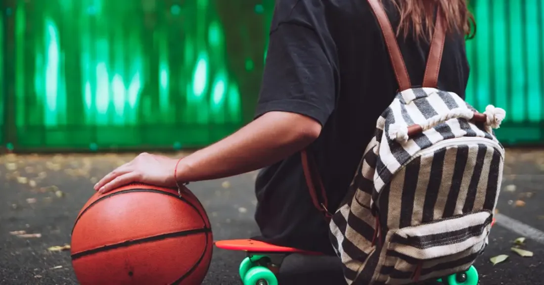 Young athlete sitting on a skateboard with a basketball, ready to return to sport after hip arthroscopy